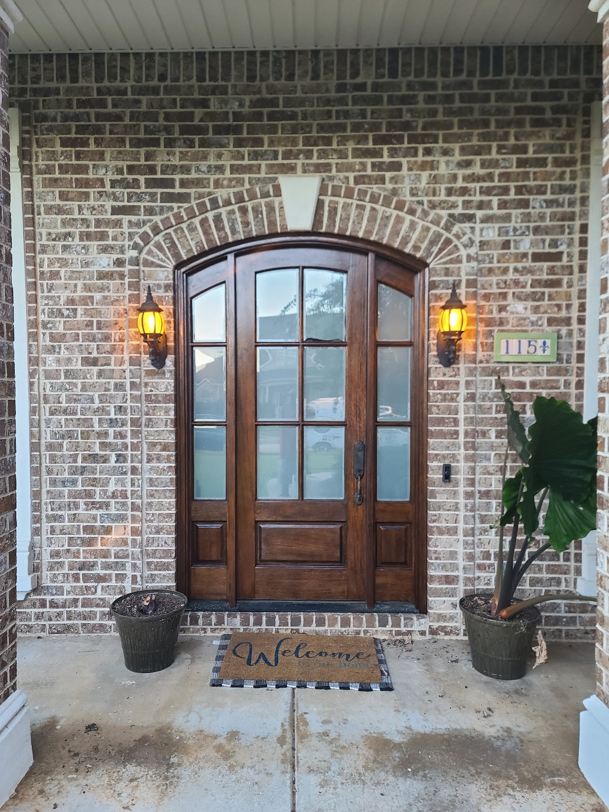 Stained arched wooden front door in a brick entry